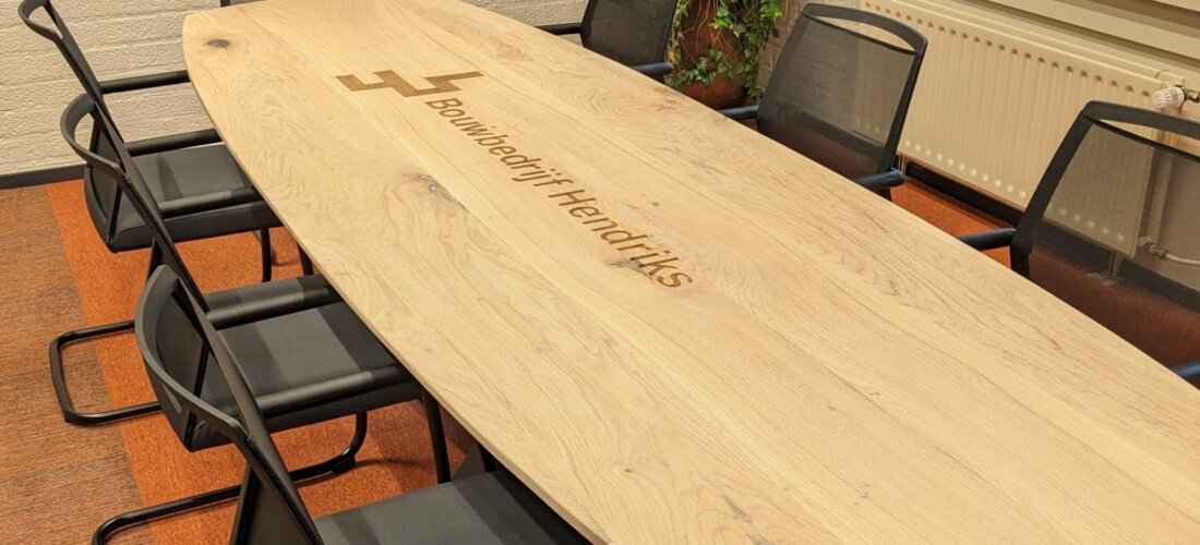 Ovale vergadertafel met logo in directiekamer Bouwbedrijf Hendriks Gemert
