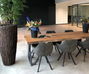 Maatwerk boomstam vergadertafel met ingegoten epoxy-logo Huisman Gemert