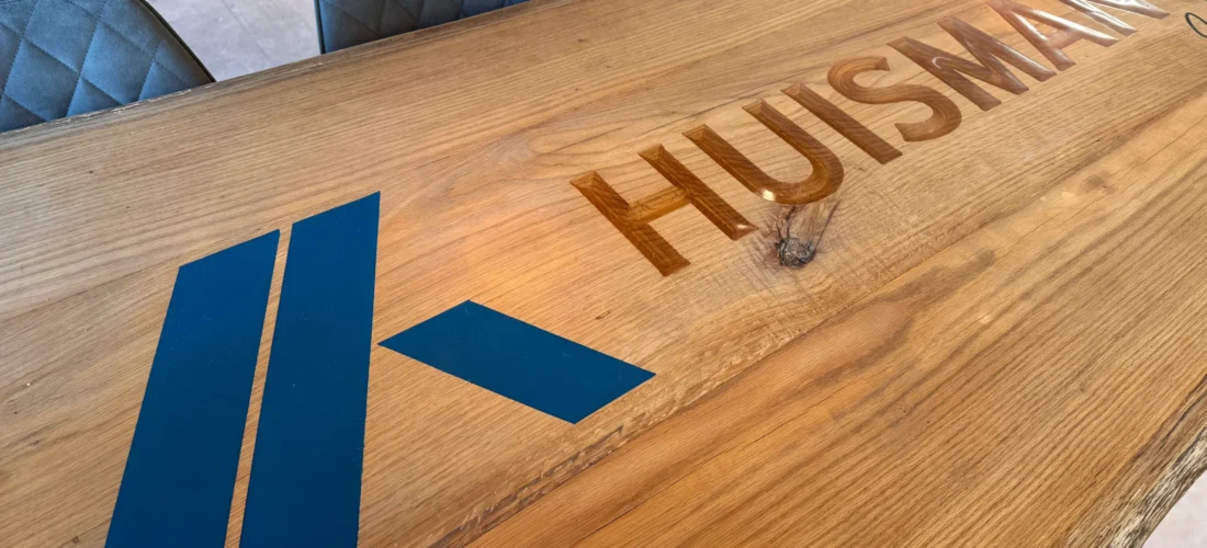 Close-up van maatwerk vergadertafel met ingegoten bedrijfslogo in massief hout